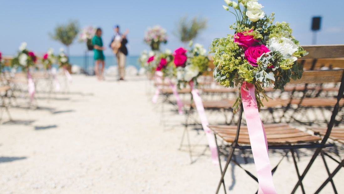 A beach wedding with a bouquet of flowers attached to a chair