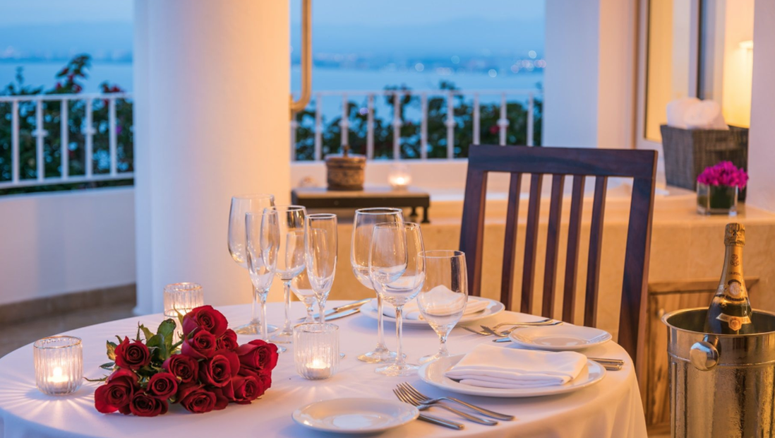 A romantic dinner table set for two, with roses and champagne 